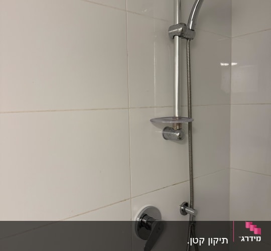 ראש מקלחת ומתקן על קיר אריחים לבנים